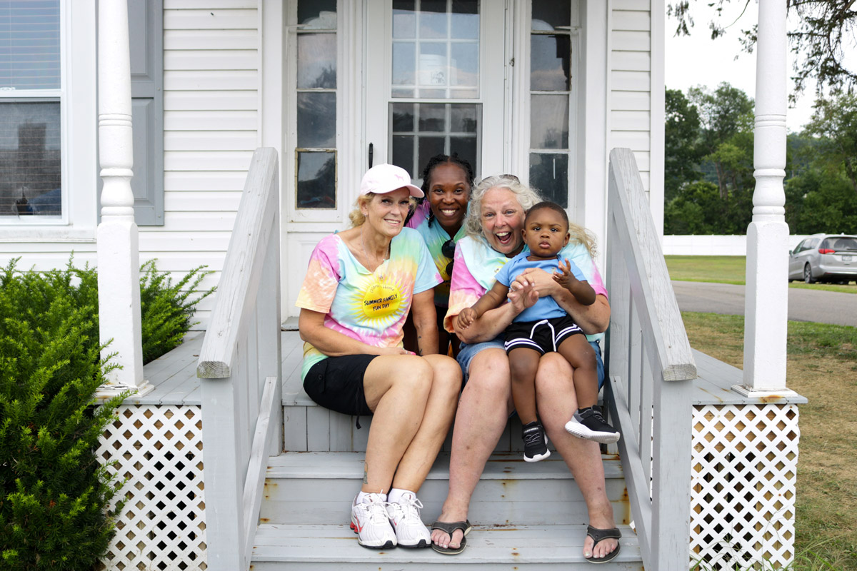 Members of the Children's Home seated on an outdoor patio hold a small child